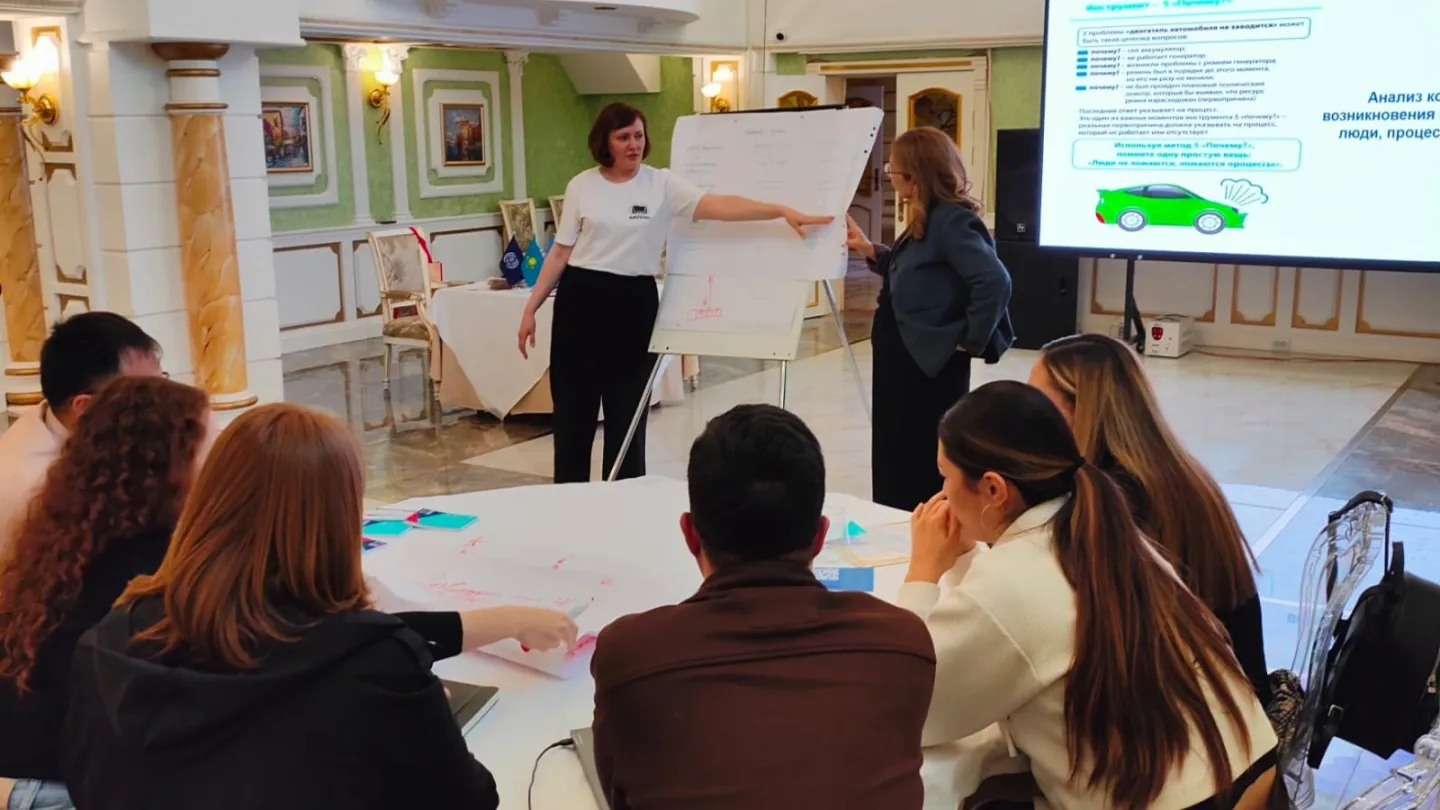 A woman presents information on a flip chart with participants seated around a table