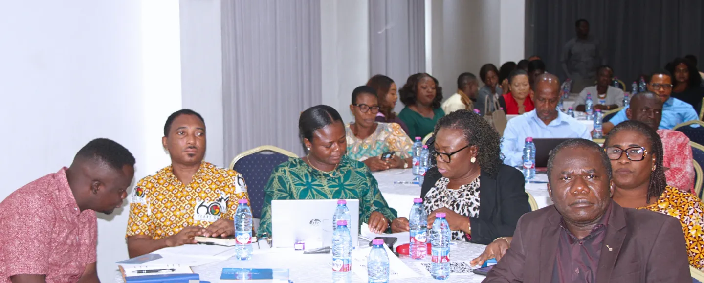 Several participants sit around a table with laptops, documents, and notebooks while discussing the results of Ghana’s trade and industrial policy assessment.