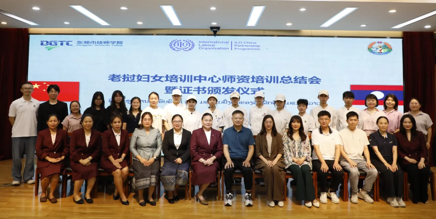 A group of trainees, instructors, and officials pose for a group photo on a stage. 