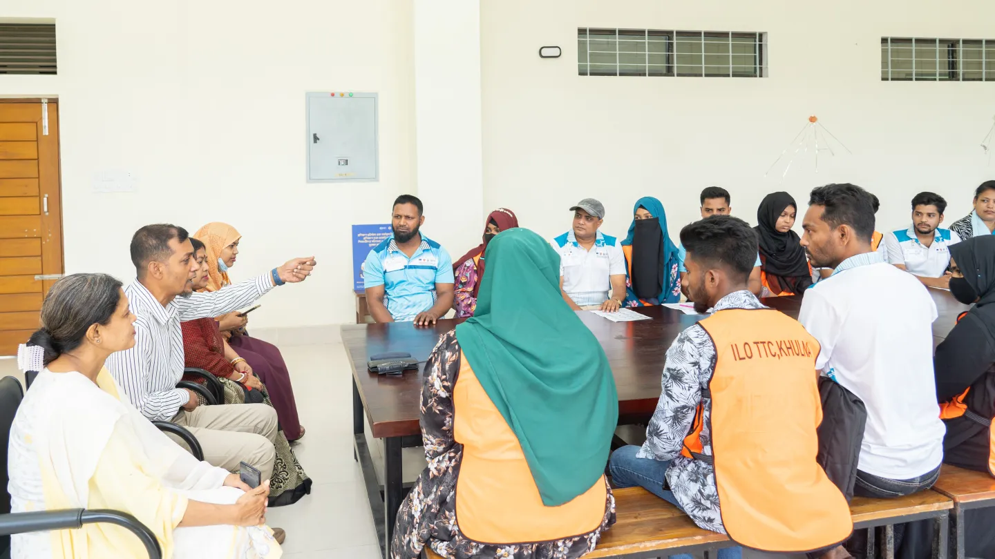 Md. Ziaur Rahman s’adresse à des stagiaires et à leurs parents réunis autour d'une grande table toute en longueur. 