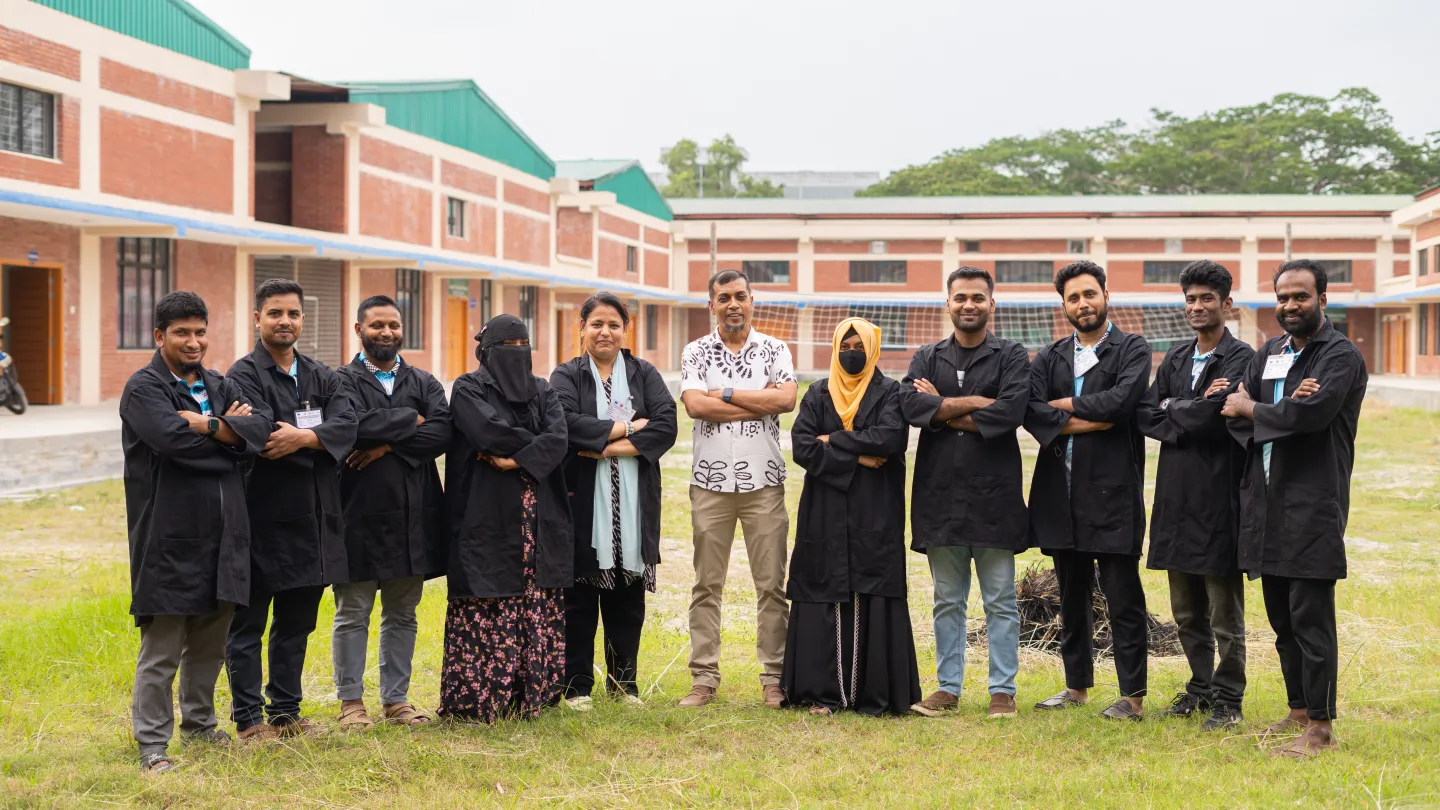 Md. Ziaur Rahman se tient au milieu d’un groupe d’étudiants et d’enseignants de son centre de formation. Ils se trouvent dans une grande cour recouverte de pelouse. Le bâtiment du centre apparaît à l’arrière-plan.