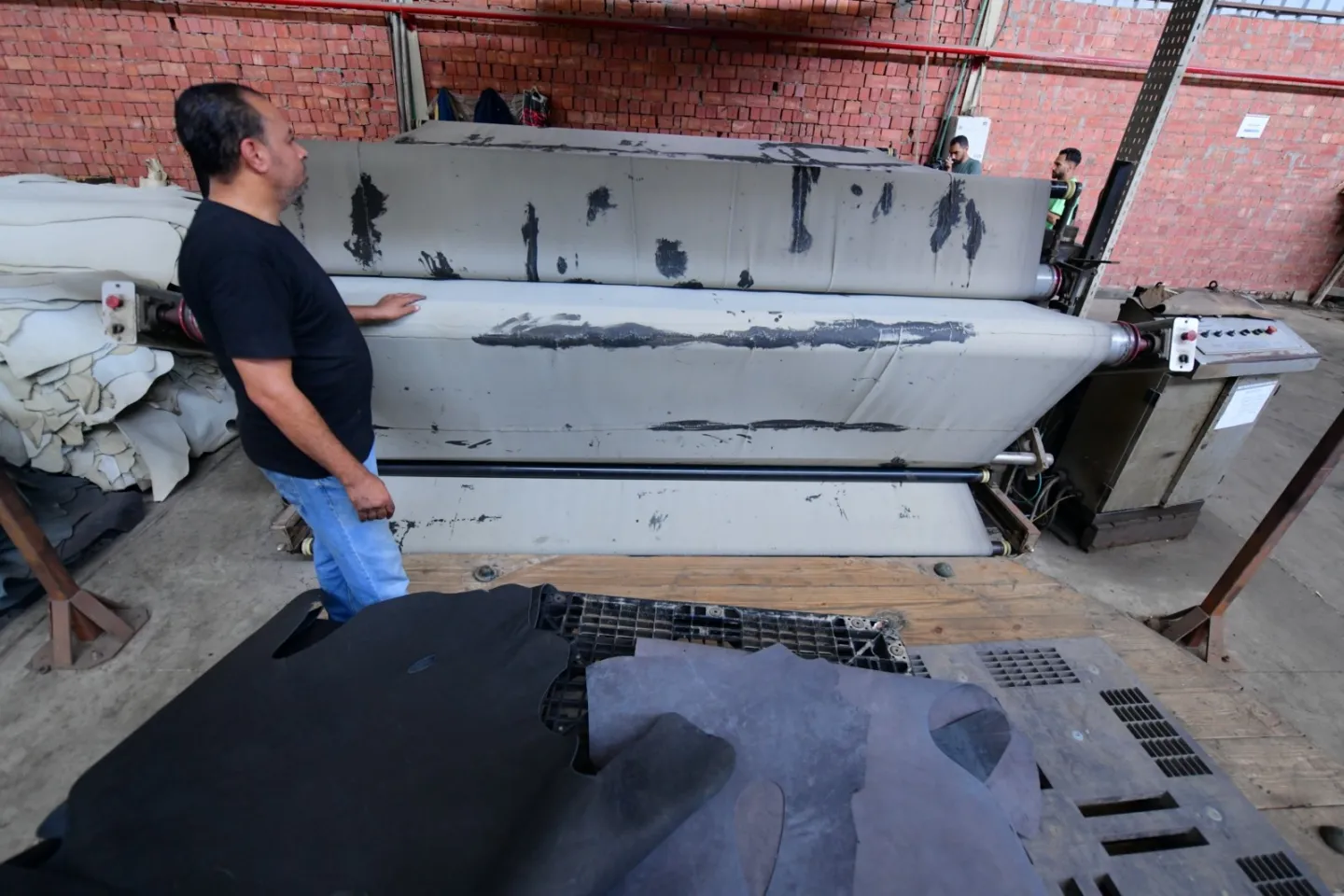 A worker operates machinery at a leather tannery.