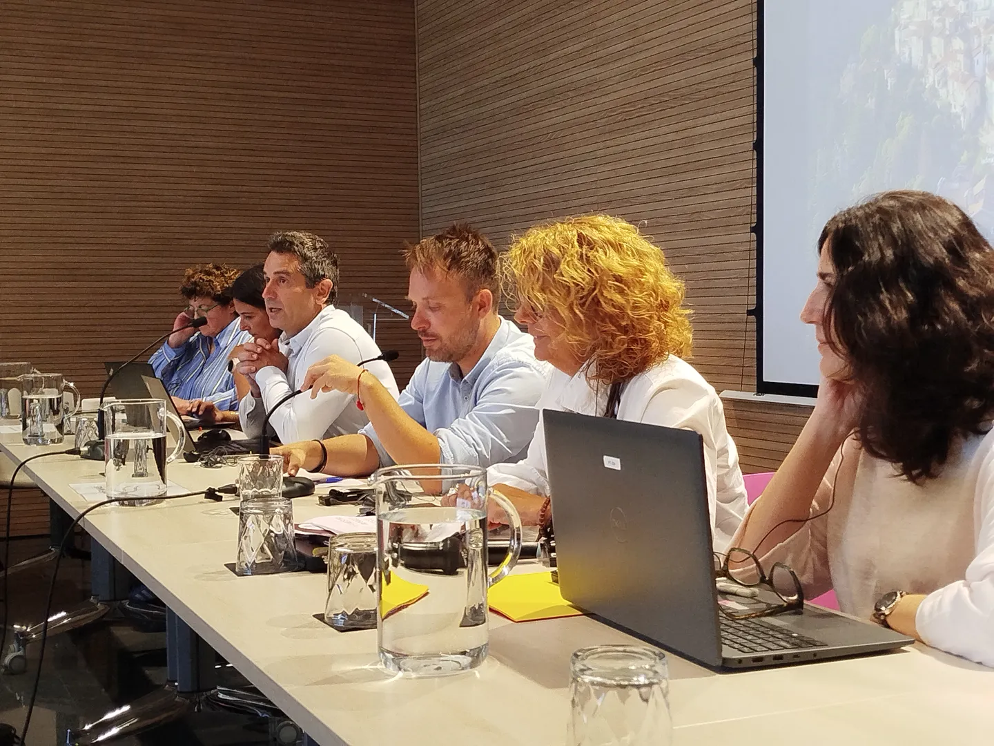 Speakers seated at a conference table contribute to a panel discussion during a workshop session. 