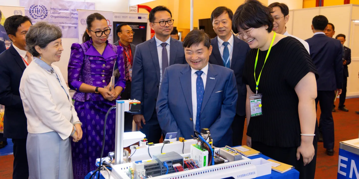A group of officials discuss the displayed equipment in an exhibition setting.