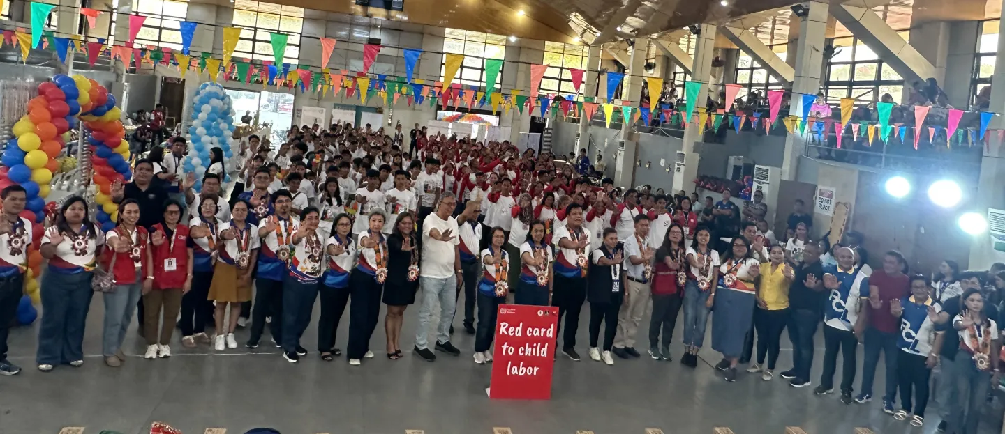 partners raide their hands to stop child labour and give a red card