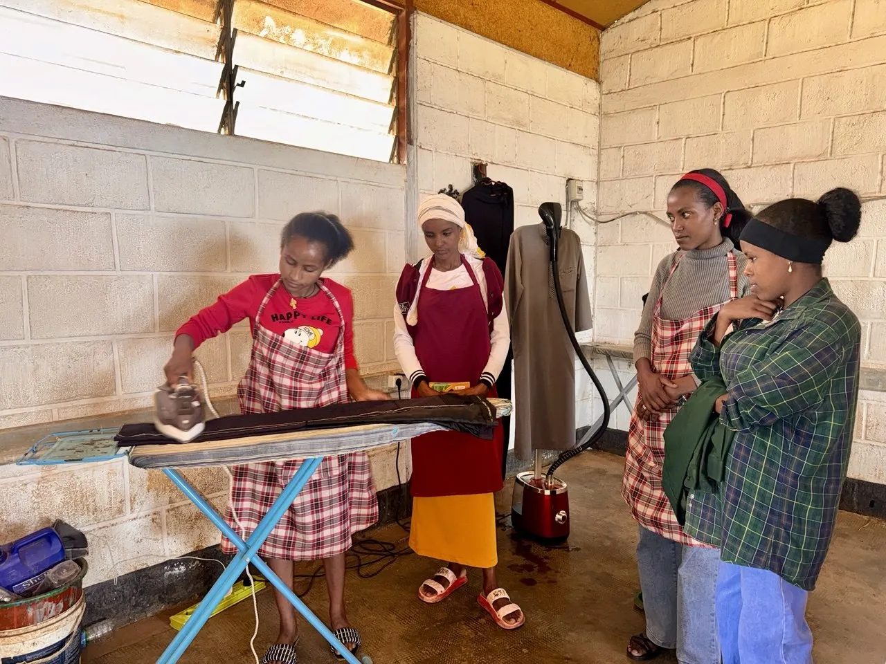 Trainees practise garment ironing during a skills training session at Assela TVET College