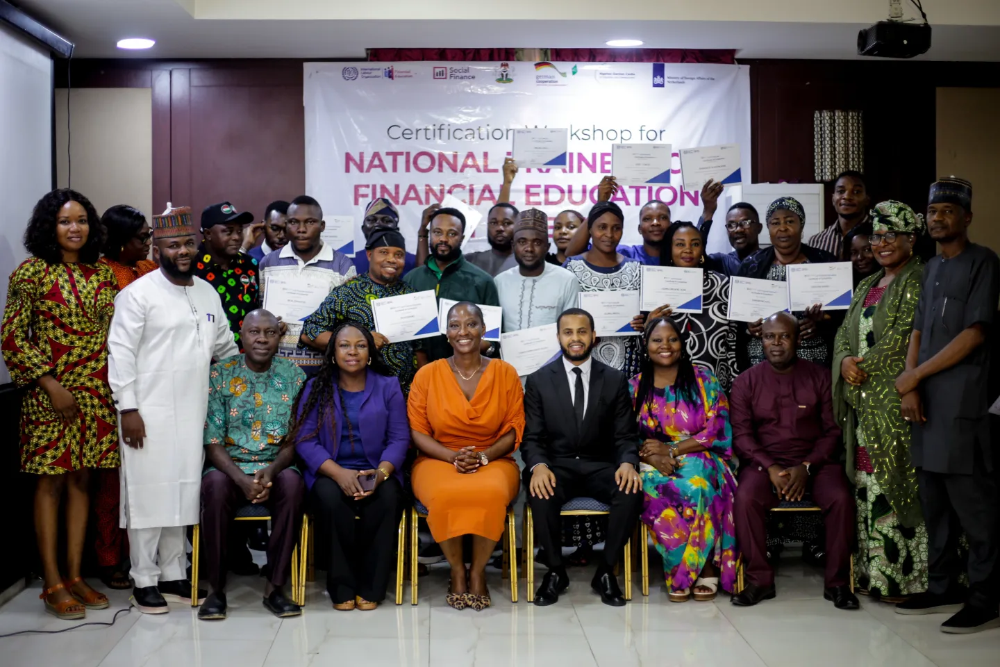 A large group of newly certified trainers proudly display their certificates alongside ILO officials and partners during a group photograph at the certification workshop.