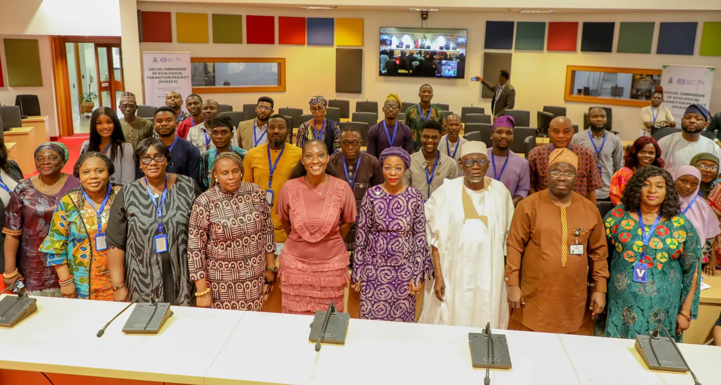 A wide view of the event's head table shows senior officials seated beneath the United Nations emblem. Event banners on both sides display the title of the ecological transition project launch.