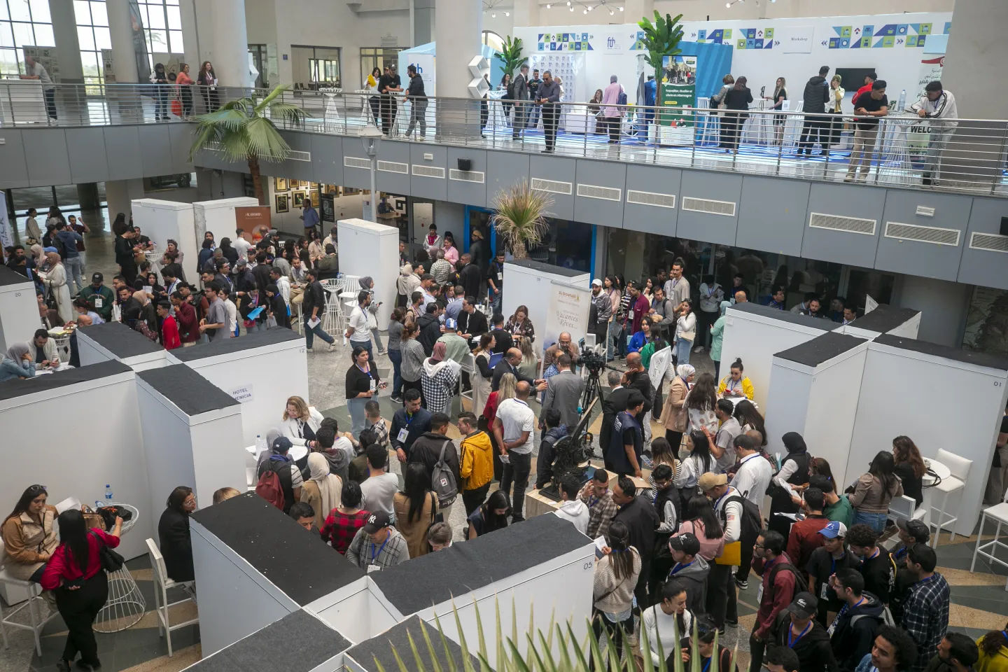 Vue d’ensemble de l’espace d’exposition du Forum tuniso-européen de l’Hôtellerie & de la Restauration. De nombreux jeunes circulent entre les stands, échangent avec les exposants et consultent les opportunités proposées par les établissements de formation, les employeurs et les institutions participantes.