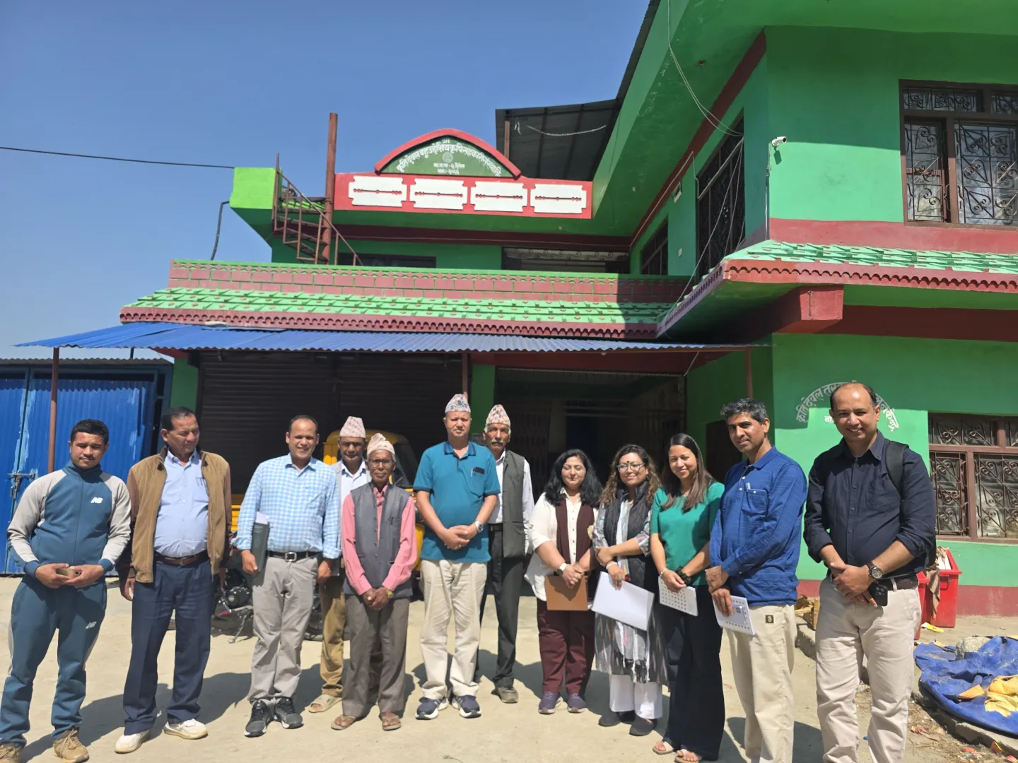 A group of people poses for a photo in front of a building. 