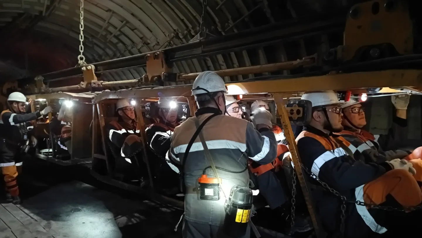 Mineros viajan sentados en un tren por el túnel de una mina.