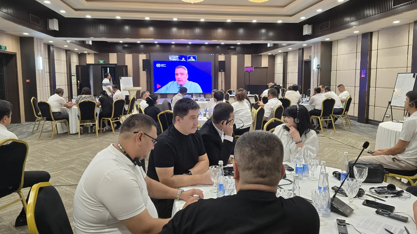 Participants seated around tables in a conference room