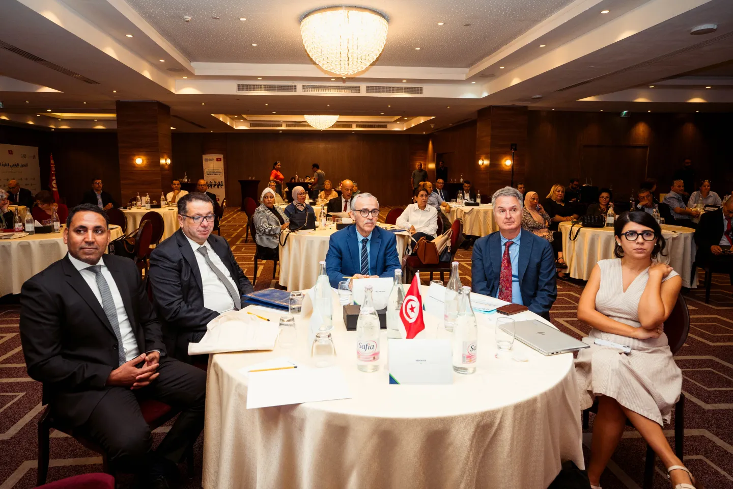 Participants réunis autour de tables lors du lancement officiel de la plateforme numérique de l’administration du travail en Tunisie.