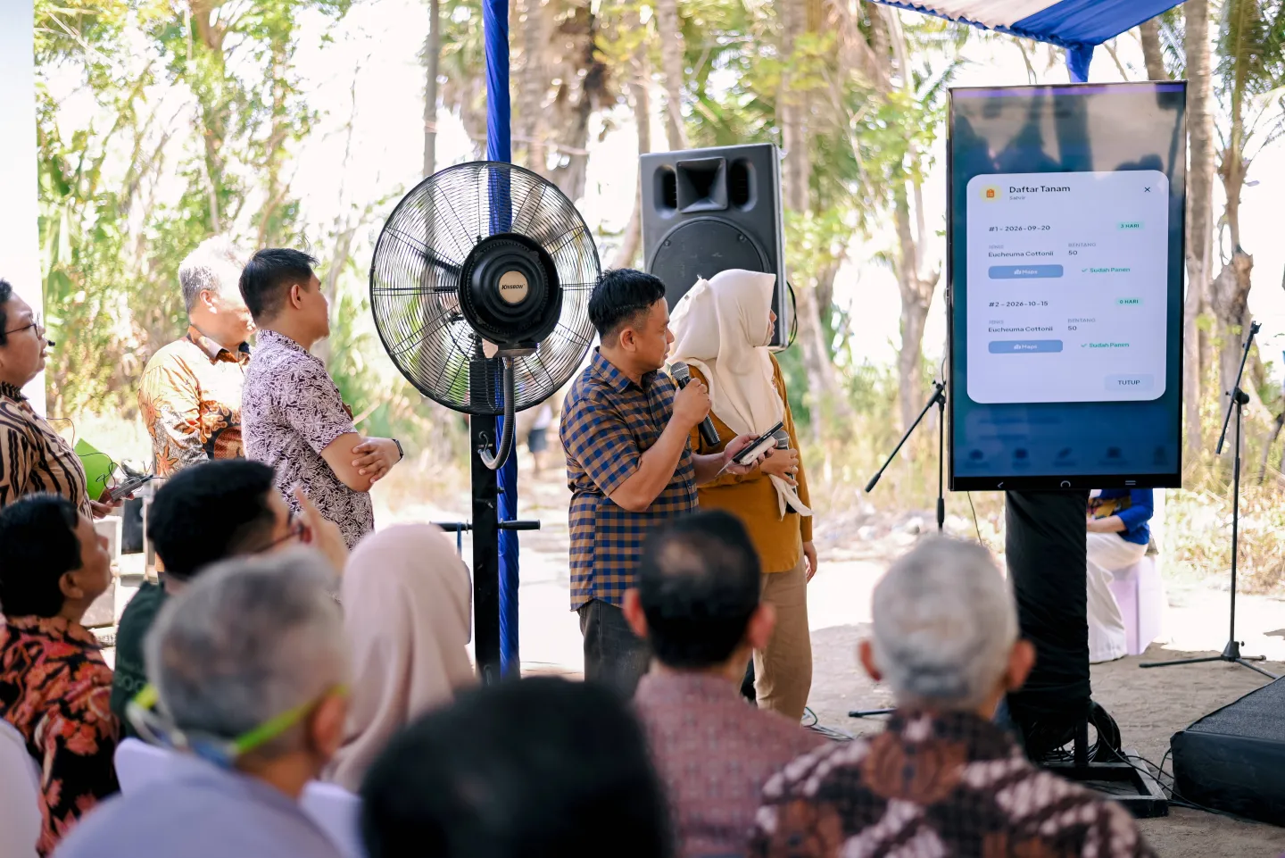 Participants watch a demonstration of the e-Seaweed digital platform on a large screen during a field visit in Ujung Baji Village, Takalar. The screen shows the platform’s interface for recording seaweed farming activities.