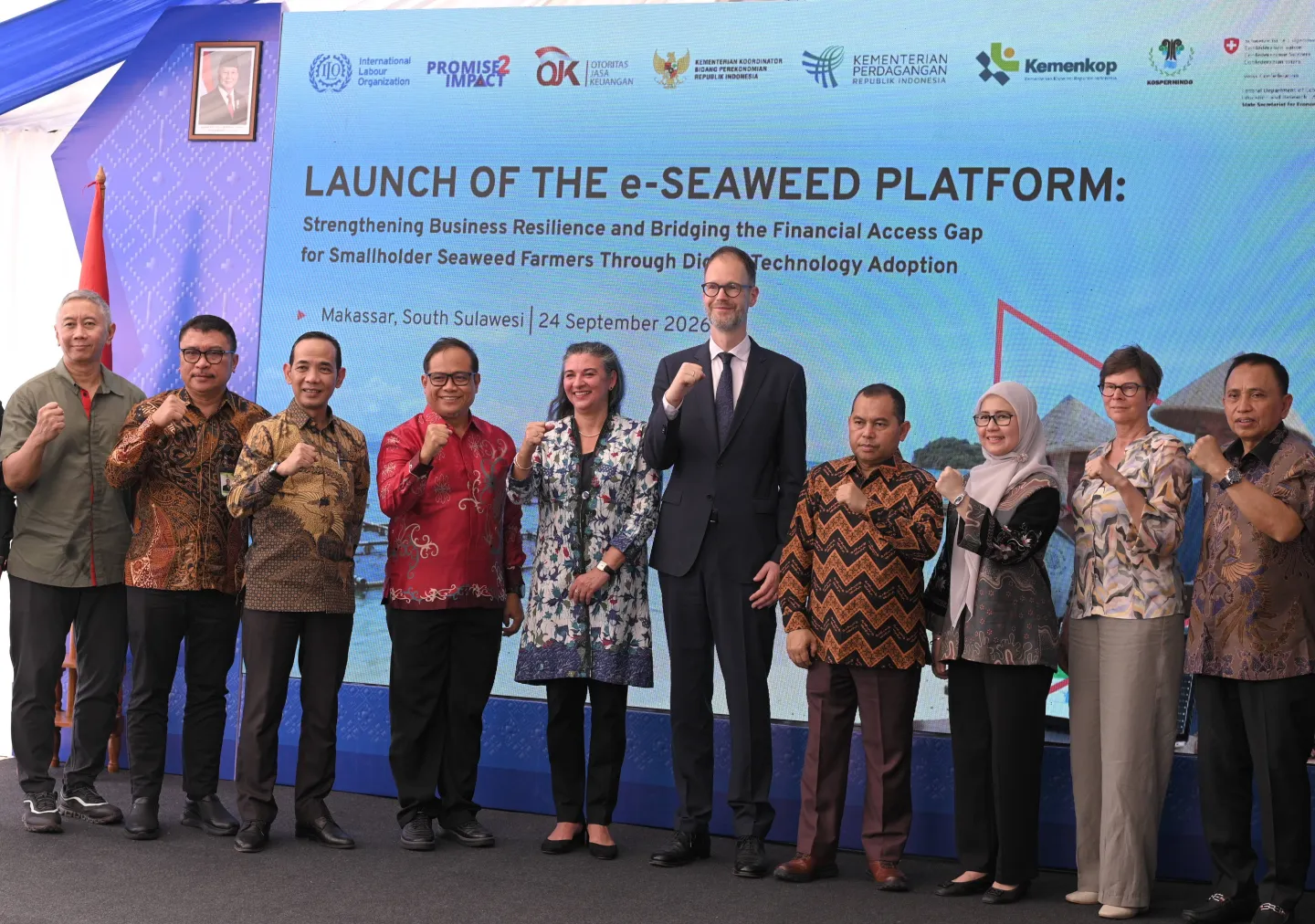 Representatives from government, the ILO and partner organizations stand together on stage at the launch of the e-Seaweed platform in Makassar, with the event backdrop behind them.