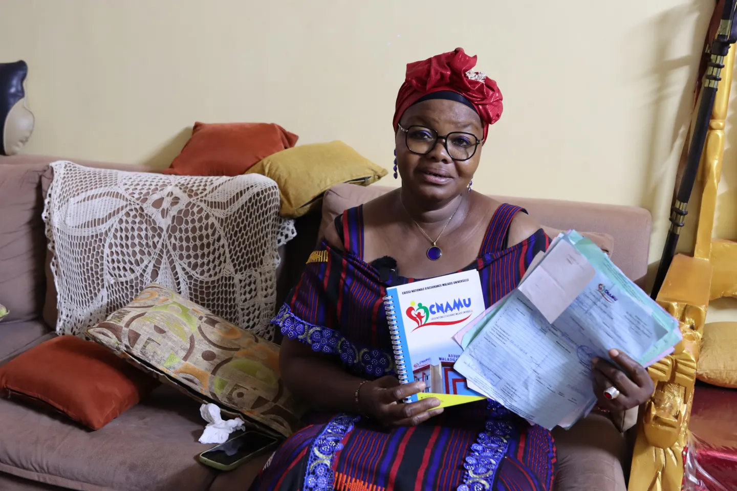 Mme Sia Fatoumata, satisfaite de la prise en charge médicale dont elle bénéficie grâce au RAMU, présente fièrement ses reçus de soins.