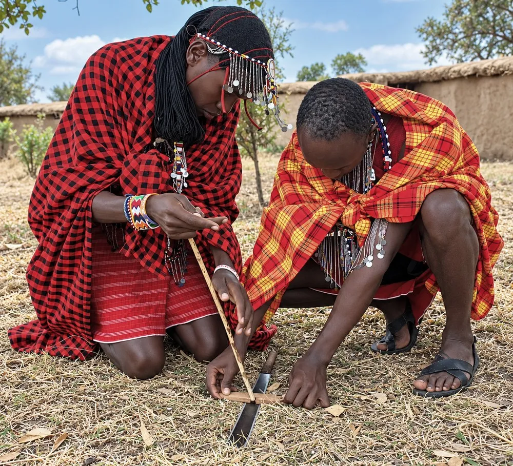 Two Maasai men demonstrate how to light a fire during a manyatta cultural visit in Emanyatta Cultural Village in Narok County.