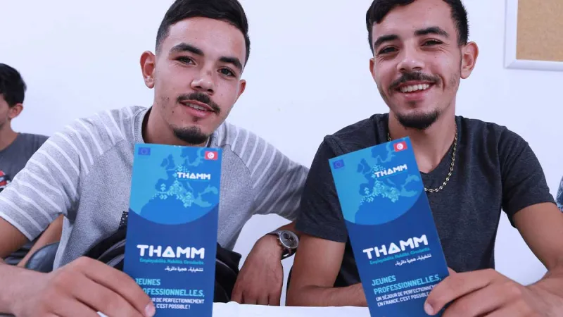 Two men holding THAMM brochure