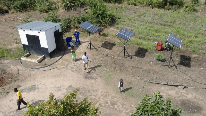 people installing solar panels next to habitation in Zambia