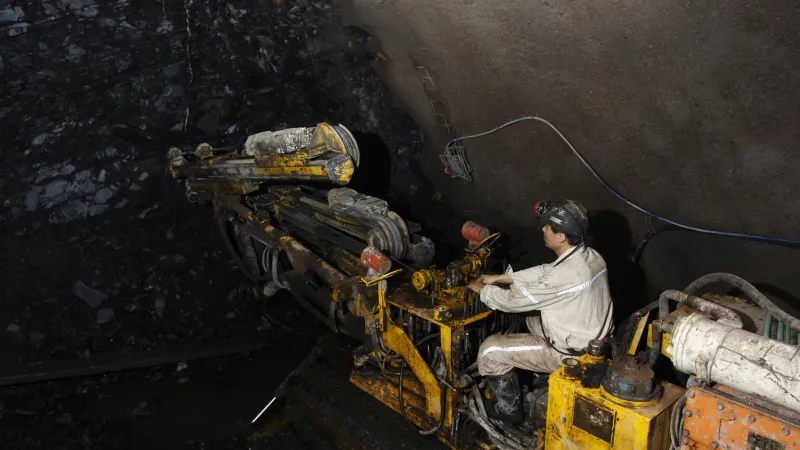 A worker is controlling a machine in a coal mine.  