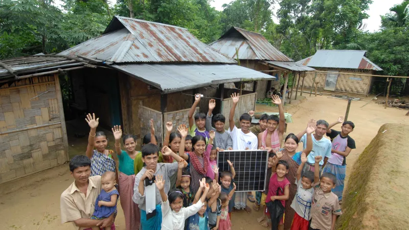 Villagers gather around a solar panel.
