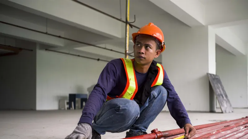 young construction male worker holding a metal and wearing a hard hat