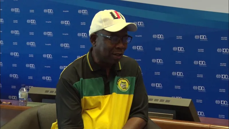 An interview participant wearing a cap and a green and yellow shirt.